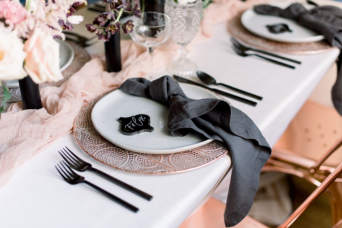 The image shows an elegant table setting with black utensils, a plate with