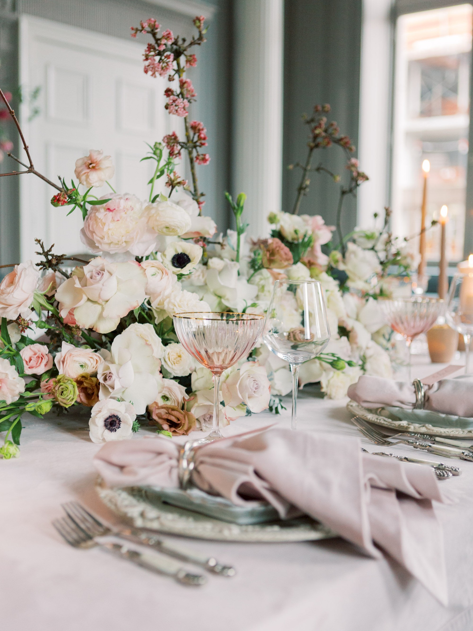 A beautifully decorated table setting with elegant floral arrangements, plates, cutlery, and wine glasses, ready for a formal dining occasion.