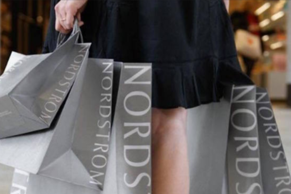 A person carries several Nordstrom shopping bags, wearing a black outfit.