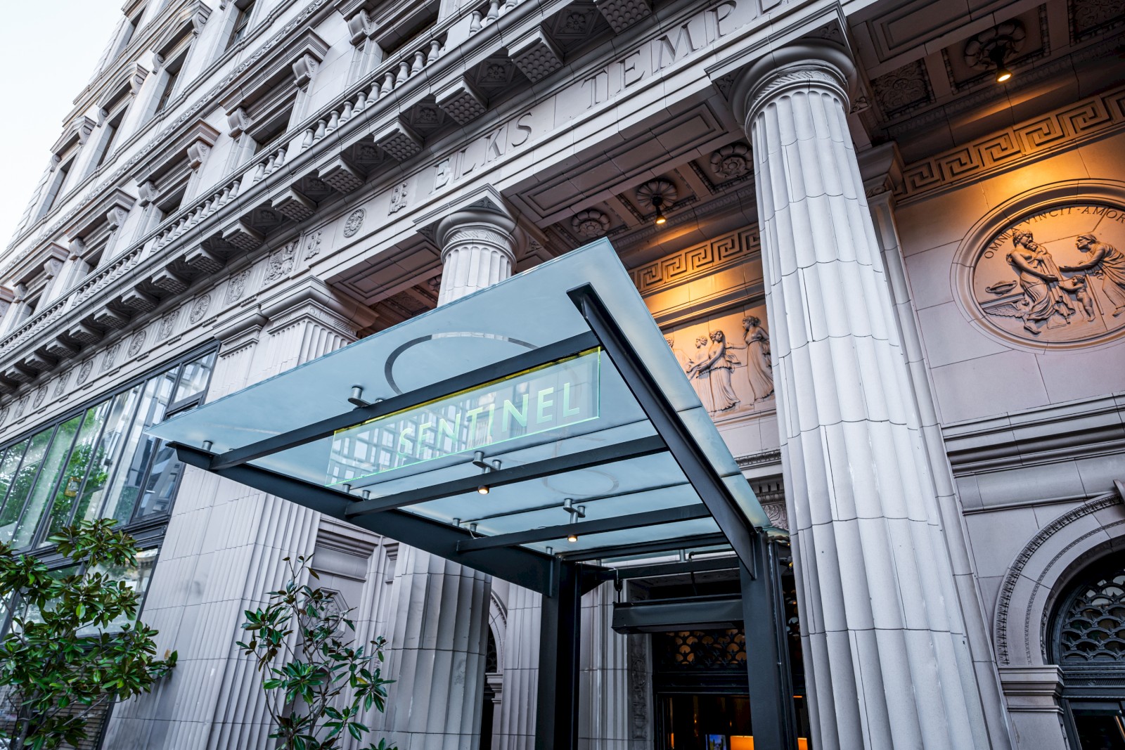 This image shows the facade of a building with classical architecture, featuring columns and a glass awning with the word 