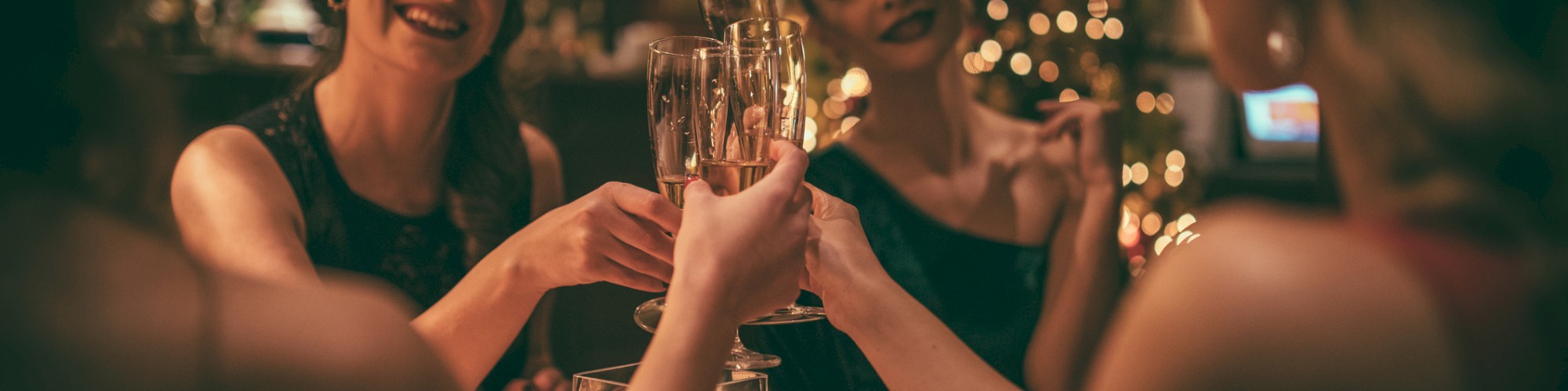 Four people are toasting with champagne in a warmly lit setting, likely celebrating a festive occasion.