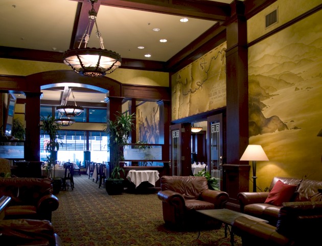 This image shows a cozy lounge area with leather sofas, warm lighting, decorative wall art, and a patterned carpet, creating an inviting ambiance.