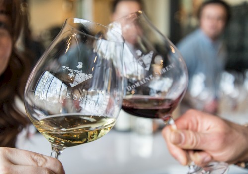 People are clinking glasses of white and red wine, with the logo 