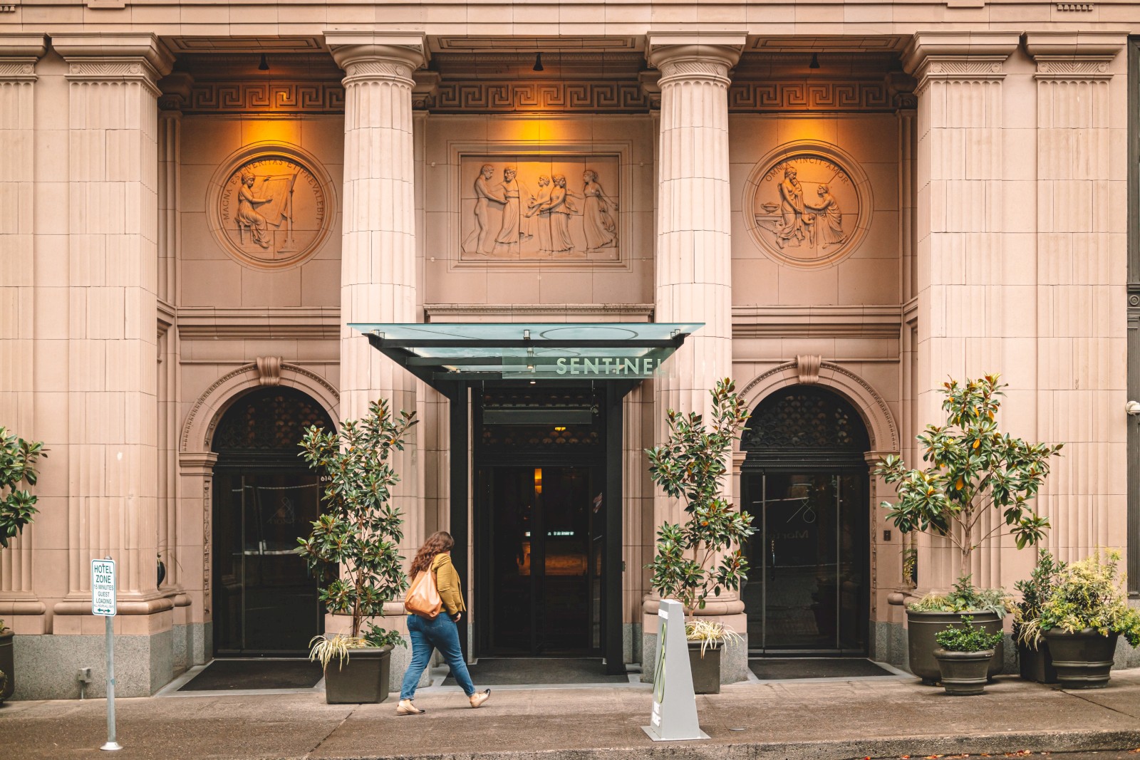 The image shows a building entrance with large columns and sculptures, labeled 
