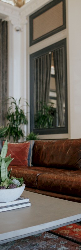 A luxurious hotel lobby with leather sofas, potted plants, and elegant curtains in a stylish, classic decor setting.